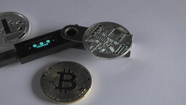 Crypto Currencies Cold hardware wallet lying with golden bitcoin coins. White background, Closeup,