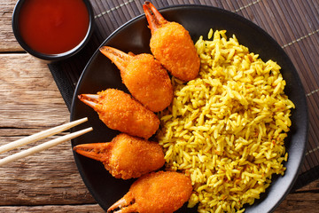 Deep fried crab claws in breadcrumbs of surimi with spicy yellow rice close-up on a plate. horizontal top view