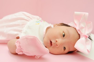 Little cute Asian girl baby lying on the floor with sweet dress and beautiful headband with blank...