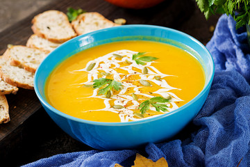 Pumpkin soup in a bowl served with parsley  and pumpkin seeds. Vegan soup.  Thanksgiving day food. Halloween meal.