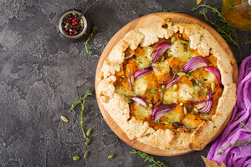 Galette pie with pumpkin and mozzarella cheese on dark background. Thanksgiving day food. Top view.