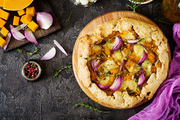Galette pie with pumpkin and mozzarella cheese on dark background. Thanksgiving day food. Top view.