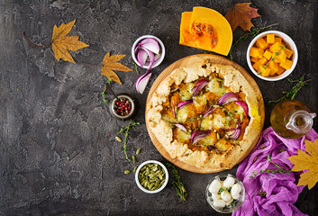 Galette pie with pumpkin and mozzarella cheese on dark background. Thanksgiving day food. Top view.