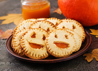 Homemade  cookies in the form as Halloween  jack-o-lantern pumpkins  on the dark table.