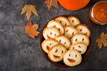 Homemade  cookies in the form as Halloween  jack-o-lantern pumpkins  on the dark table. Top view.