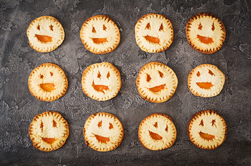 Homemade  cookies in the form as Halloween  jack-o-lantern pumpkins  on the dark table. Top view.