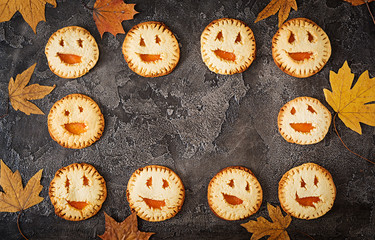 Homemade  cookies in the form as Halloween  jack-o-lantern pumpkins  on the dark table. Top view.
