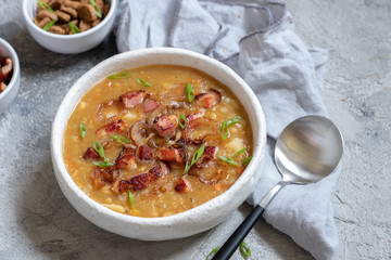 Lentil pea soup garnish with bacon, onion and croutons.