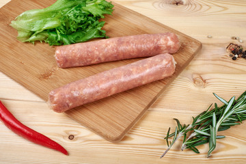 Raw sausages with vegetables and spices on wooden background