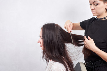 Female hairdresser makes a haircut for a woman closeup in beauty salon