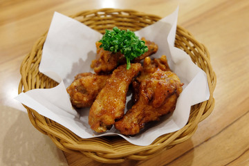 Fried chicken wings in white plate on wooden table..