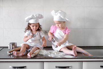 Two Little girl preparing cookies in kitchen at home