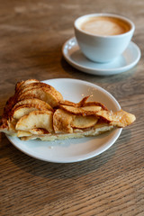 Close up of tasty sweet dessert, apple cake with cup of fresh americano coffee with milk. Autumn bake in cafe on wooden background. Concept of food.