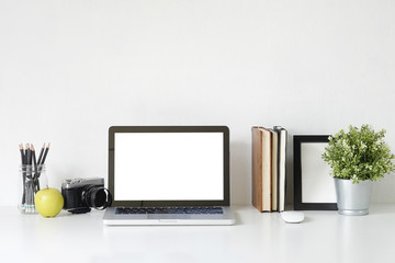 Stylish table Mockup laptop computer, camera, book and photo frame on white desk with office supplies.