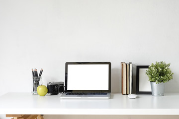 Stylish table Mockup laptop computer, camera, book and photo frame on white desk with office supplies.