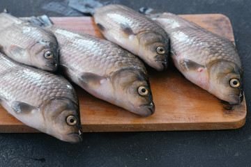 Cooking fish. Fresh small carps on the table on a wooden Board close-up.