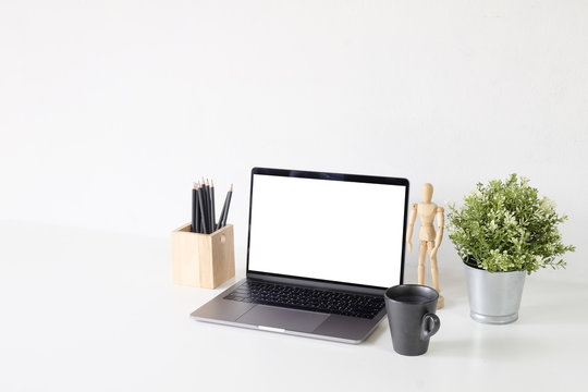 Mockup laptop computer on white isolated table with office supplies.