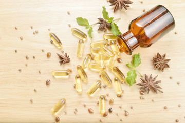 Obraz na płótnie Canvas Fish oil capsules with omega 3 and vitamin D spread out of a brown glass bottle on wooden texture, healthy diet concept.