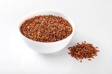 Bowl of red raw rice and a pile of rice isolated at white background.