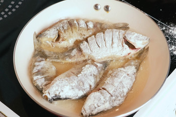 Fish carps fried in oil in a pan.