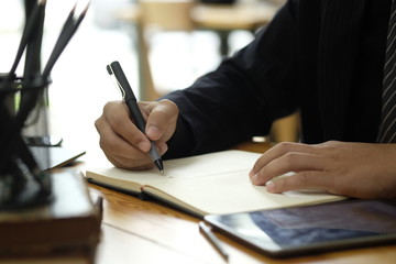 Cropped image of hand of businessman writing notes on desk at office