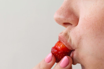 Woman eats strawberries. Mouth close-up. Side view.
