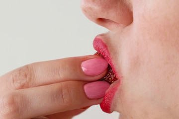 Woman with red lips eats strawberries. Mouth close-up. Side view.