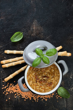Pot of italian thick soup with pasta and lentils on a dark brown stone background, top view with copyspace, vertical shot