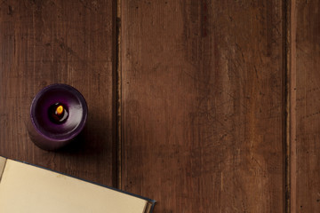 An detail of an old book with a candle on a dark rustic background with copy space