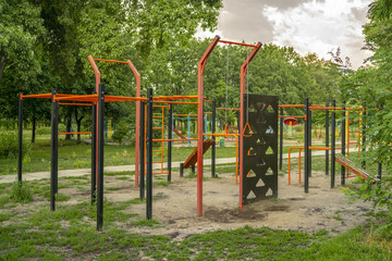 Fototapeta na wymiar Empty sports ground with various training apparatus in the green city park without people