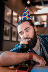 Sipping beer. Funny bearded man feeling not bored while sipping some dark beer celebrating birthday
