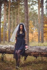 Halloween Witch in a dark forest. Beautiful young woman in witches modern dress . Halloween art design. Dark theme For Halloween Concept 