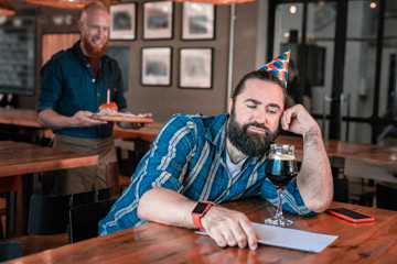 Feeling cheerless. Dark-haired handsome stylish man feeling cheerless waiting for friends on birthday