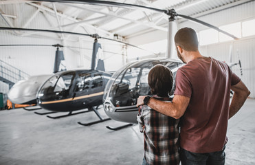 Fototapeta na wymiar Father hugging son while watching at rotorcraft. They turning back to camera