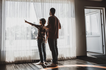 Full length cheerful boy gesticulating hand while telling with satisfied father. They looking at...