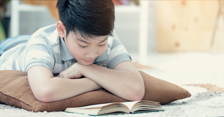 Asian boy reading book with smile face.