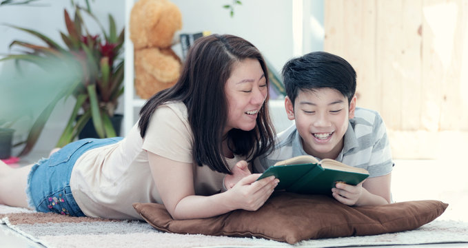 Asian mother with son reading book together with smile face.