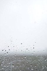 Rainy, autumn weather outside the window. Drops of water on the glass on a blurred background. Romantic grubby topic. Stock photo for design