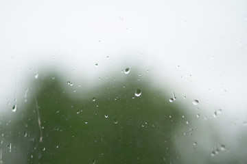 Rainy, autumn weather outside the window. Drops of water on the glass on a blurred background. Romantic grubby topic. Stock photo for design