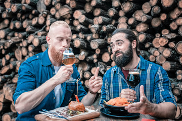 Beer with snacks. Two bearded men fond of gastronomy enjoying nice craft beer with tasty snacks