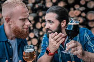 Beer and communication. Two bearded friends communicating while having some craft beer sitting on summer terrace
