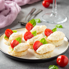 Canape with cheese mousse, cherry tomato and basil, small sandwich on crispy toast with cheese and garlic dumplings. Delicious appetizer, wine snack