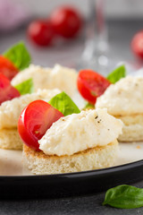 Canape with cheese mousse, cherry tomato and basil, small sandwich on crispy toast with cheese and garlic dumplings. Delicious appetizer, wine snack