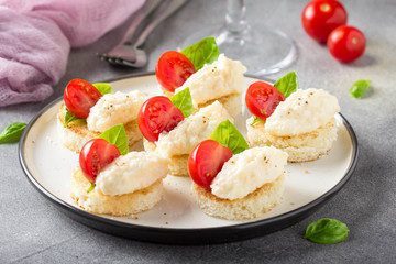 Canape with cheese mousse, cherry tomato and basil, small sandwich on crispy toast with cheese and garlic dumplings. Delicious appetizer, wine snack