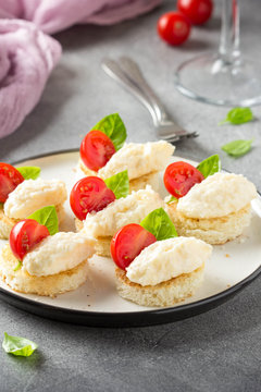 Canape with cheese mousse, cherry tomato and basil, small sandwich on crispy toast with cheese and garlic dumplings. Delicious appetizer, wine snack