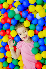 Fototapeta na wymiar happy little girl having fun in ball pit with colorful balls.