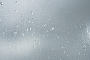 Rainy, autumn weather outside the window. Drops of water on the glass on a blurred background. Romantic grubby topic. Stock photo for design