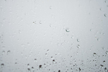 Rainy, autumn weather outside the window. Drops of water on the glass on a blurred background. Romantic grubby topic. Stock photo for design