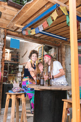 Young hippies. Two modern young hippies wearing stylish bright clothes sitting in nice alcohol bar