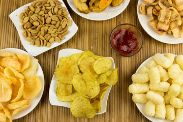 Peanut, Snack, nut, potato chips  on a plate. Wooden table. Salty food for beer